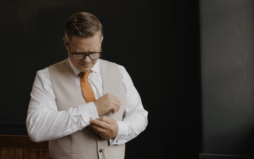 Rich adjusts his cufflinks at the boys room in Crowcombe Court
